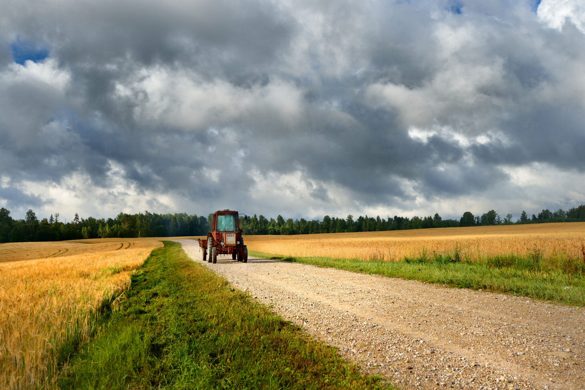 tractor-on-the-road-and-cereal-field-against-dark-stormy-clouds-SBI-300735946-2048x1367.jpg